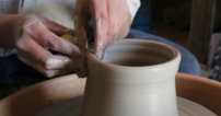person holding brown clay pot